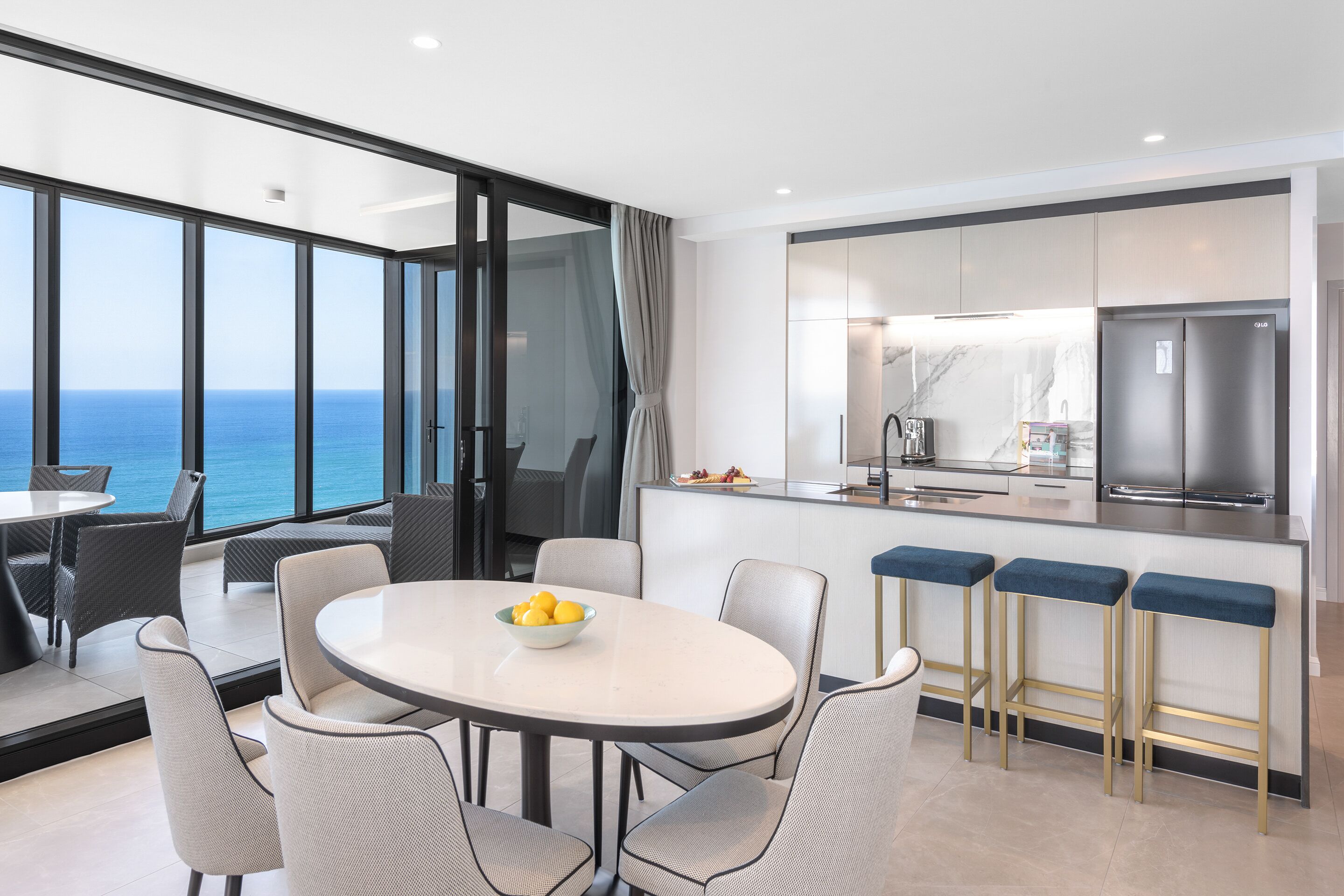 Una cucina moderna con una grande isola, sgabelli da bar e vista sull'oceano.