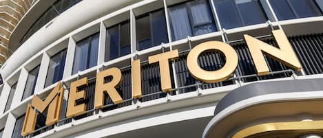 Un hôtel dont l’enseigne « MERITON » est bien visible à l’extérieur.