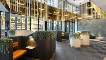 A modern interior with seating areas, vertical light fixtures, and a geometric wall pattern.