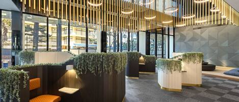 Un intérieur moderne avec des espaces de détente, des luminaires verticaux et un motif géométrique sur le mur.