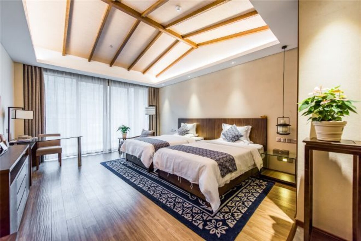 Habitació d'hotel moderna amb dos llits, un escriptori i una finestra gran.