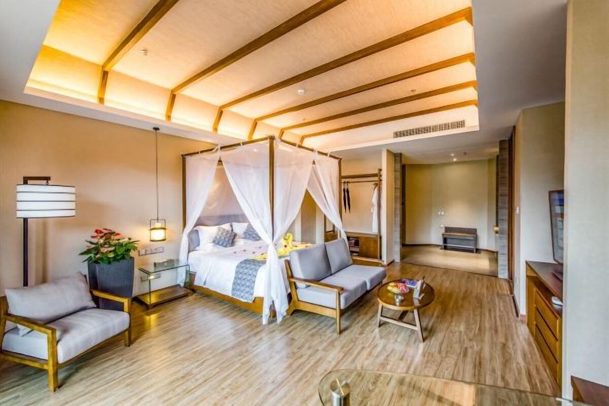 A modern bedroom with a canopy bed, bedside tables, a sofa, and a small coffee table.
