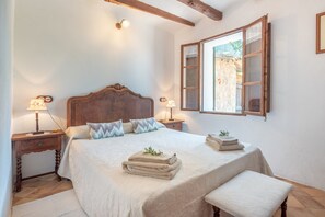 Une chambre à coucher avec un lit en bois, des lampes de chevet, une fenêtre donnant sur un beau paysage et une table de chevet avec une lampe.