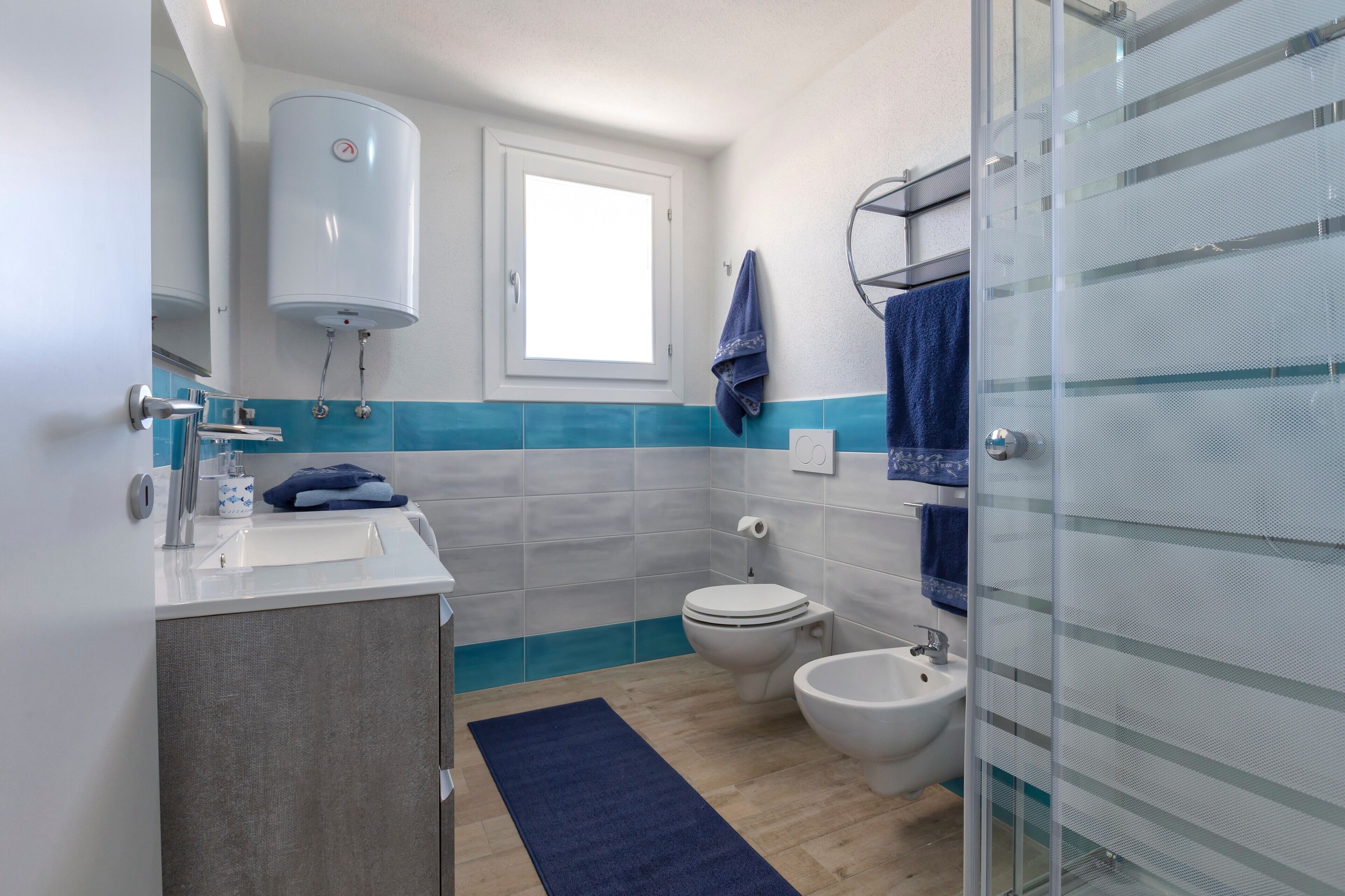 Un bany amb vàter, bidet, rentapel i una dutxa amb envàs de vidre.