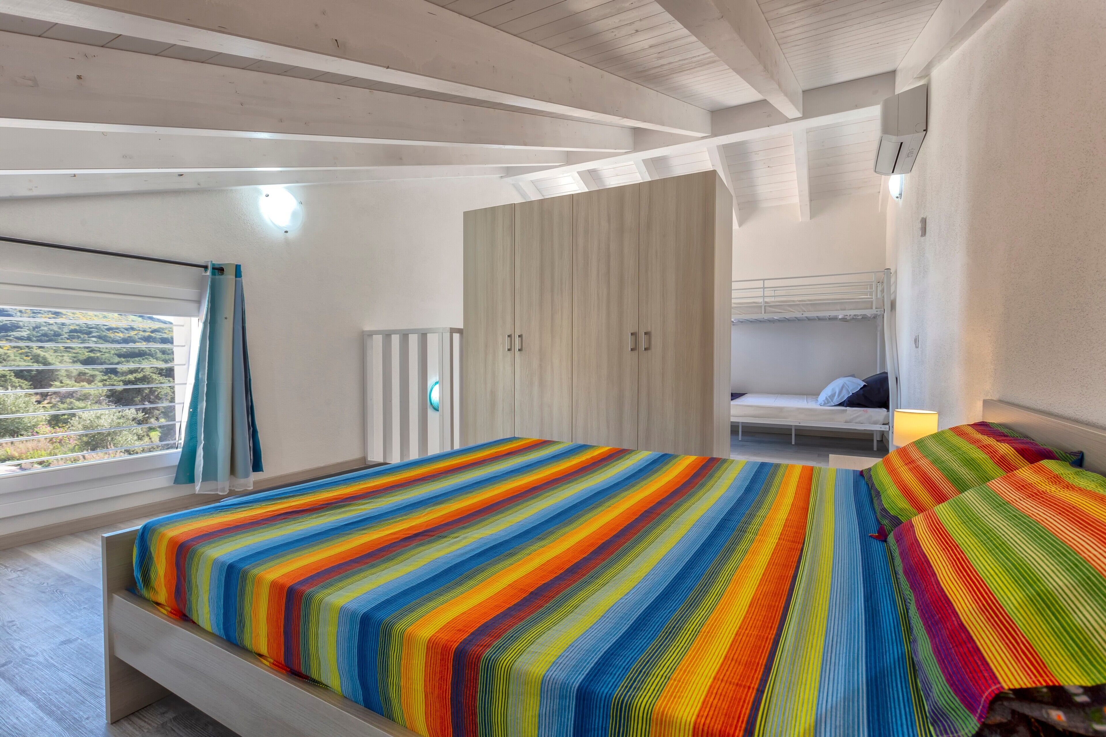 Ein modernes Schlafzimmer mit einem großen Bett, einem Kleiderschrank und einem Etagenbett.