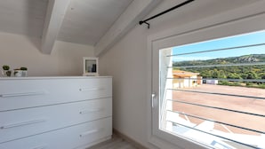Una habitación con un aparador blanco, una puerta con vistas y un techo con vigas de madera.
