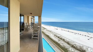 Un balcon avec des chaises et une piscine donnant sur une plage.