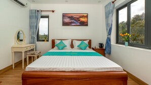 A bedroom with a wooden bed, a bedside table with a mirror, a window with curtains, and a painting on the wall. - Sala Hotel (Ho Chi Minh City)