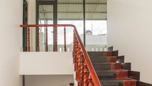 A multi-level staircase with wooden balusters and red handrails, leading to a balcony with a view of the sky. - Sala Hotel (Ho Chi Minh City)