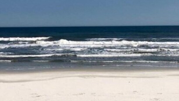 Ein Strand mit blauem Himmel und Meereswellen.