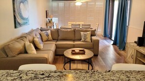 Ein Wohnzimmer mit Ecksofa, Couchtisch und Essbereich mit Tisch und Stühlen.