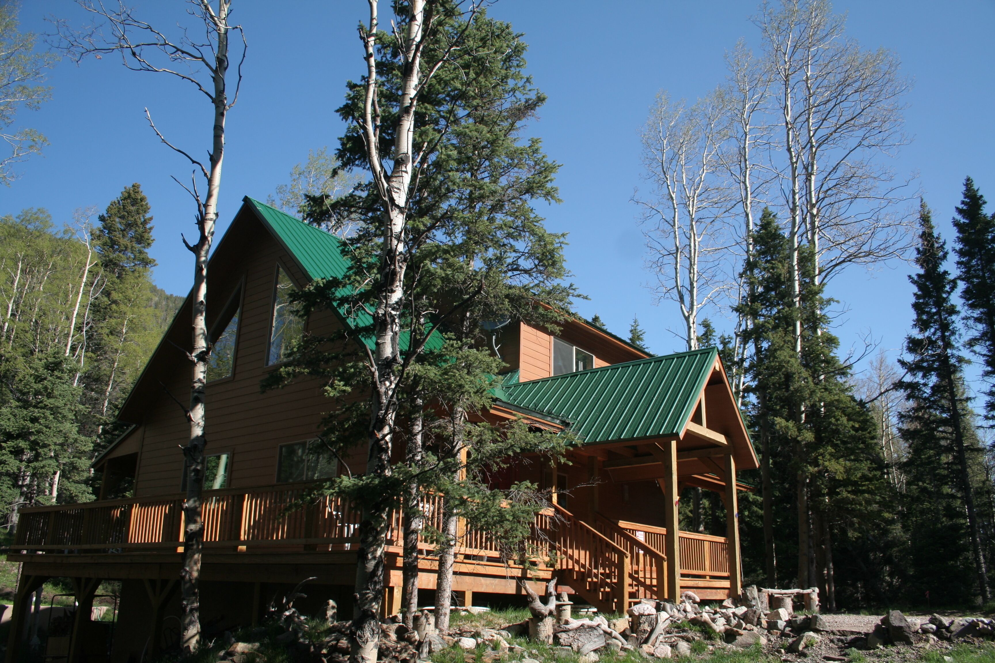 Une cabane en rondins surmontée d’un toit végétalisé, entourée d’arbres.