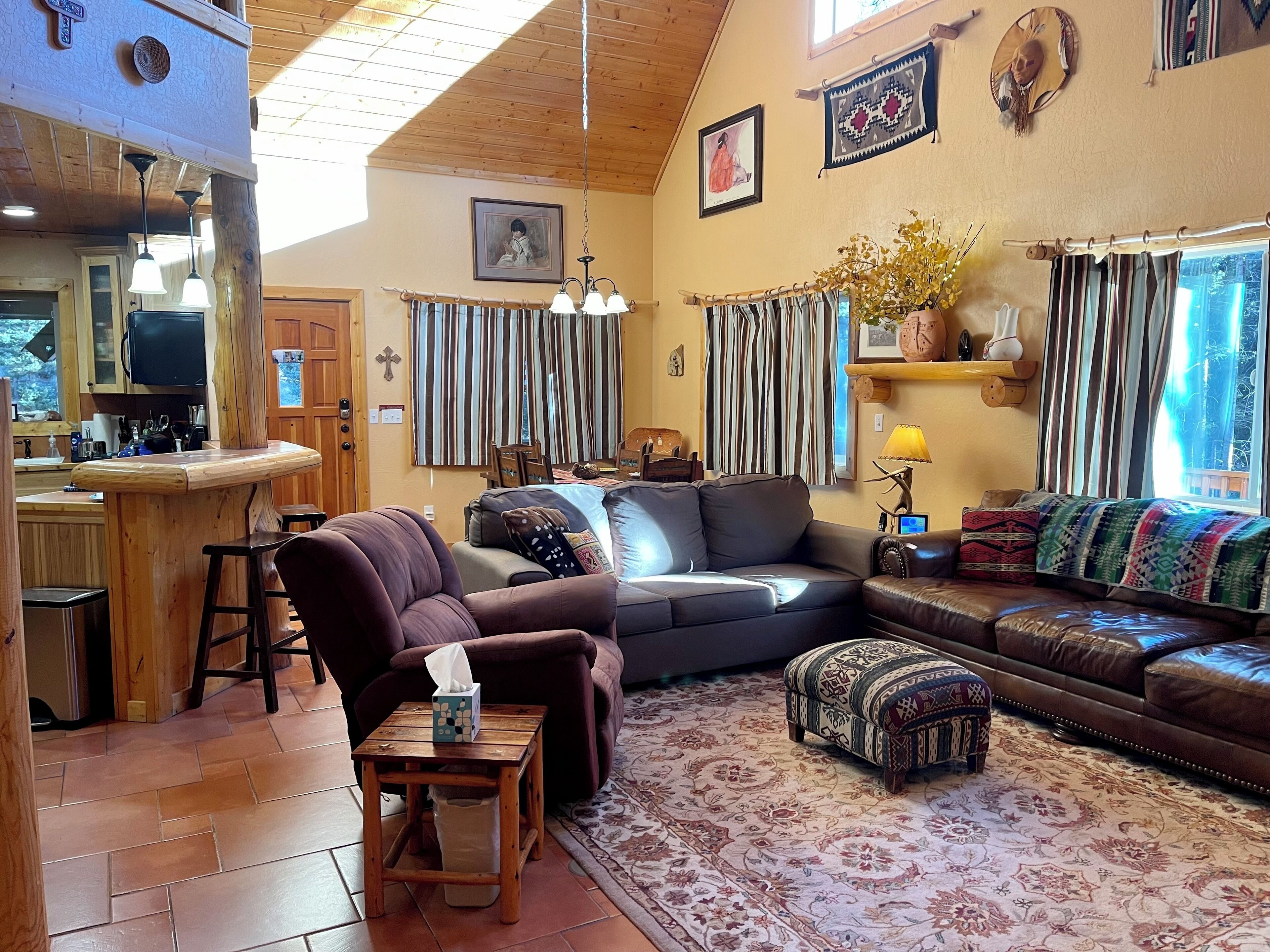 Una sala de estar acogedora con techo de madera, un sofá, una mesa de centro y una alfombra.