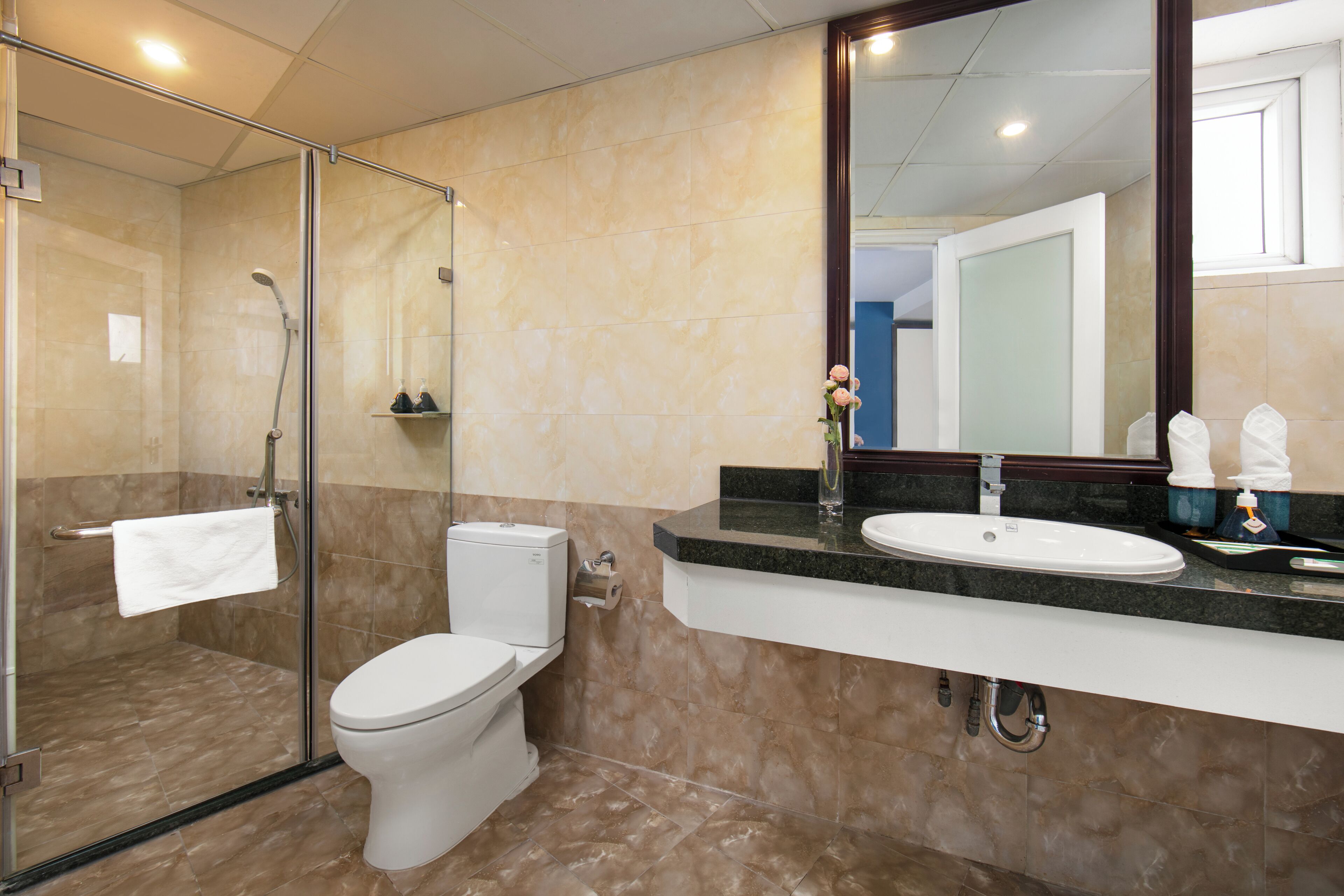A modern bathroom with a glass-enclosed shower, a white toilet, and a vanity with a sink and mirror.