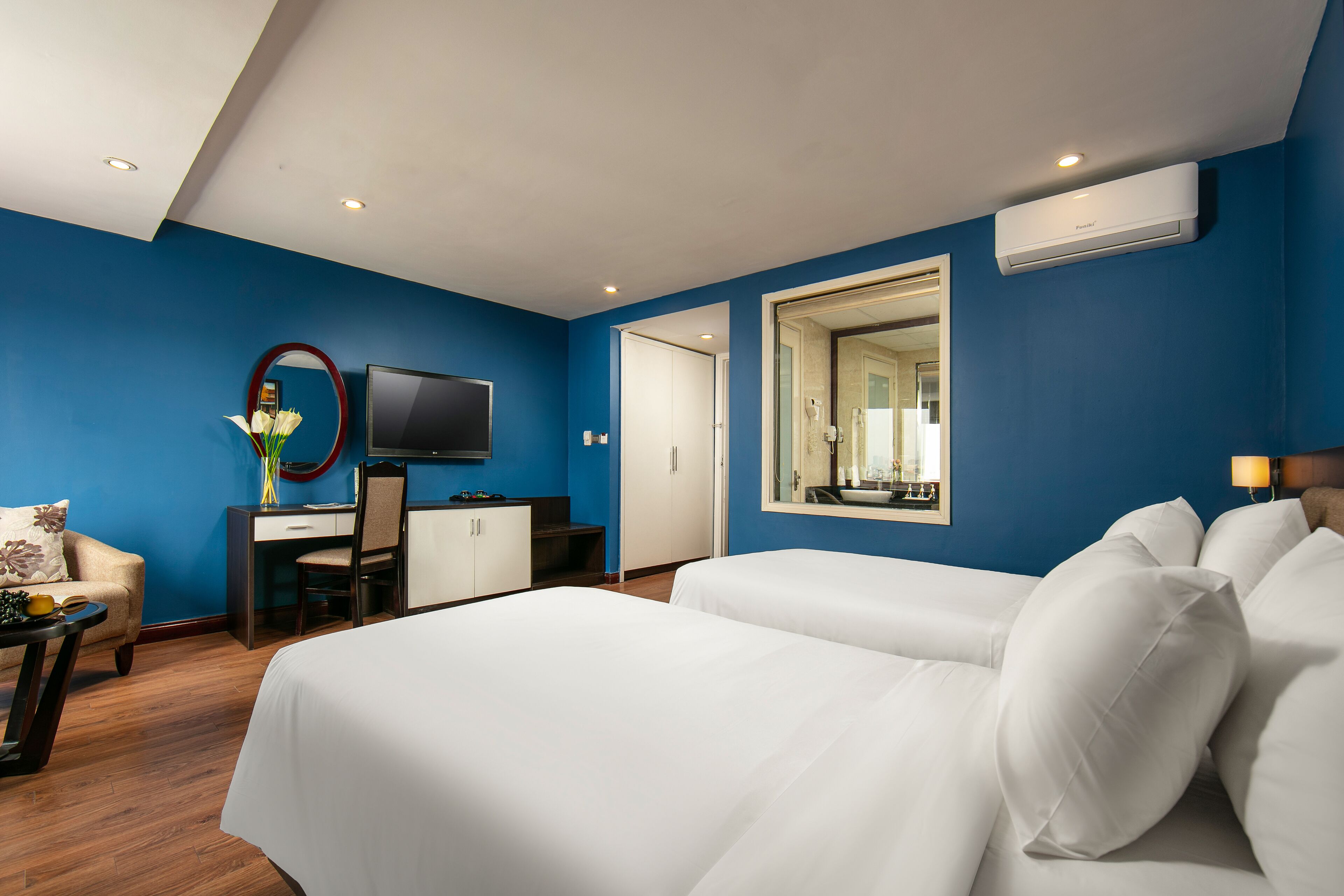 Habitació d'hotel amb un llit gran, una taula de treball amb una cadira, una televisió i un mirall.