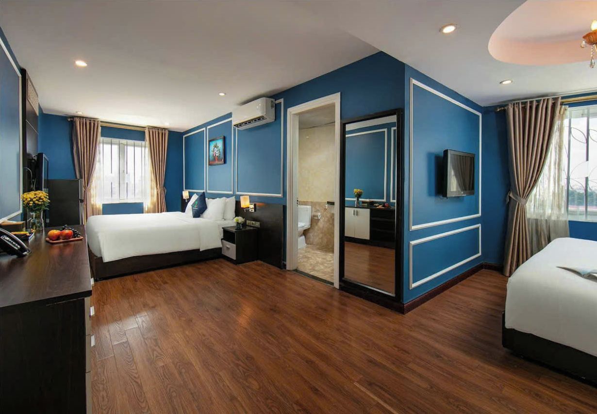 A modern hotel room with a large bed, a desk with a computer, and a TV.