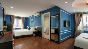 A modern hotel room with a large bed, a desk with a computer, and a TV.