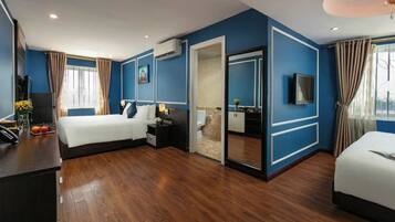 A modern hotel room with a large bed, a desk with a computer, and a TV.