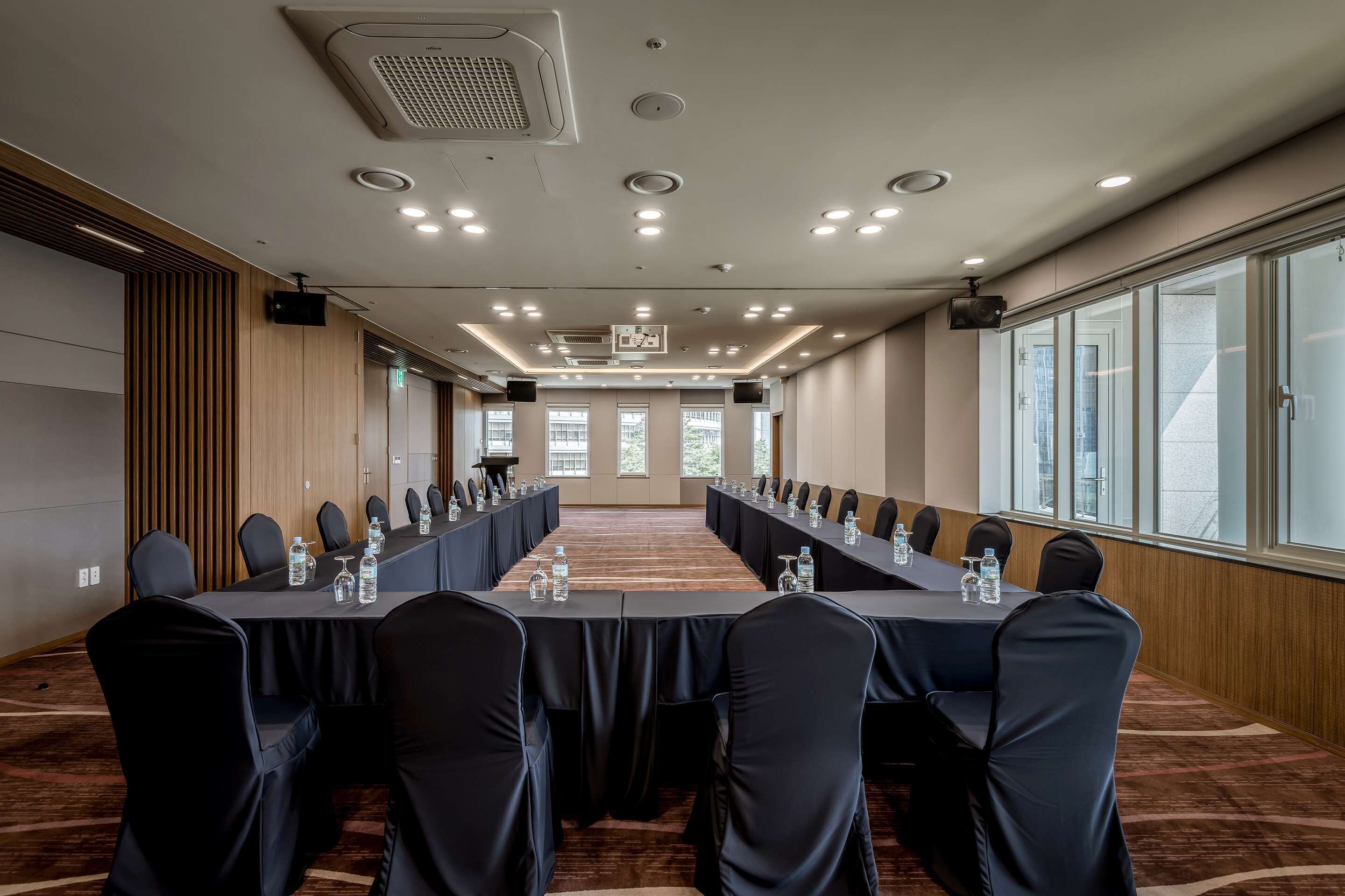 A conference room with a long table, black chairs, and water bottles.