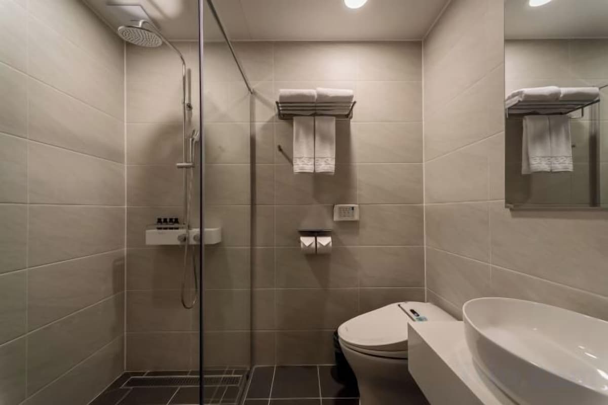 A bathroom with a glass-enclosed shower, a toilet, and a sink.