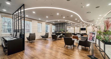 Un moderno vestíbulo de hotel con una recepción, zona de estar y un bar.