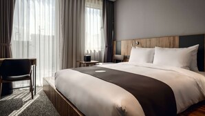 Una habitación de hotel con una cama grande, un escritorio, una silla y una mesita.