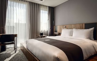 Una habitación de hotel con una cama grande, un escritorio, una silla y una mesita.