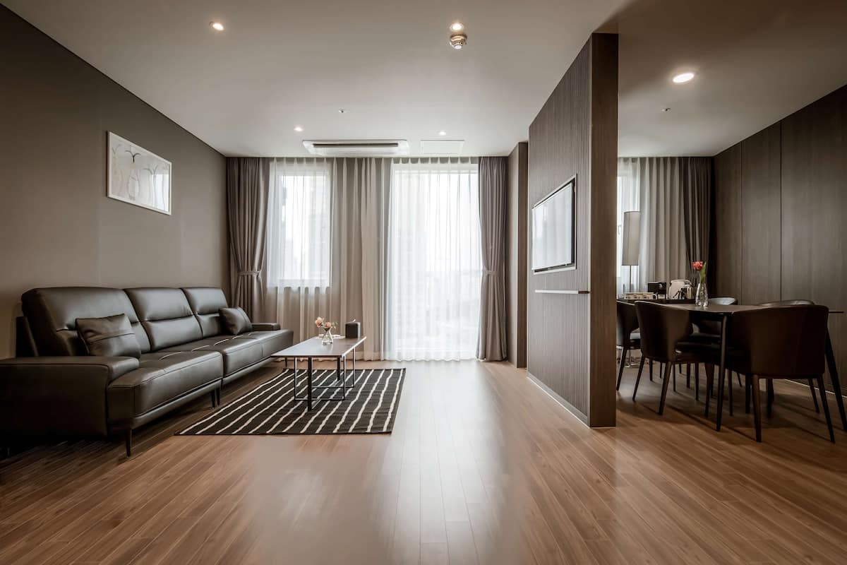 A modern living room with a leather sofa, a dining table, and a TV.