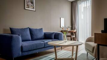 A modern living room with a blue sofa, a round coffee table, and a dining area with a table and chairs.