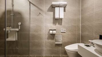 A modern bathroom with a glass-enclosed shower, a toilet, and a sink.