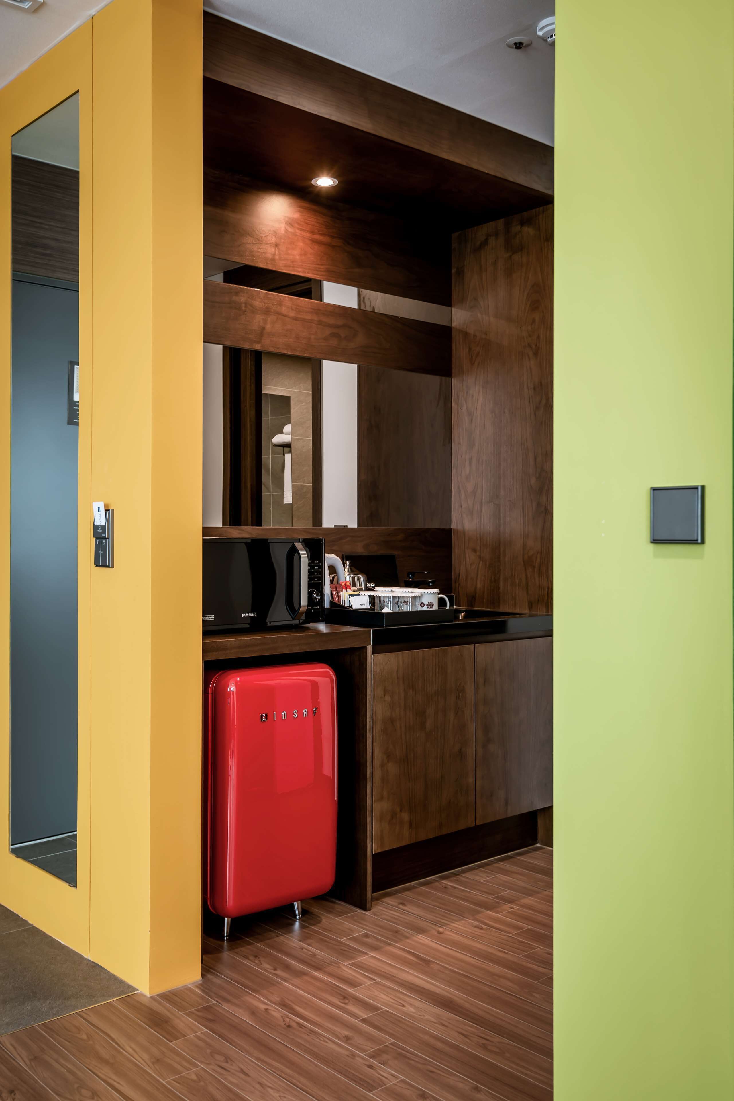 A compact kitchen with a microwave, toaster, and red mini-fridge.