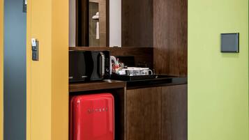 A compact kitchen with a microwave, toaster, and red mini-fridge.