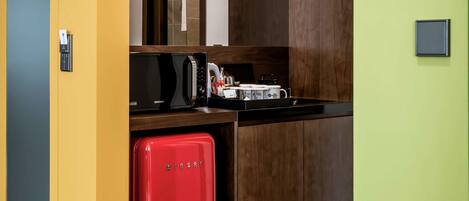 Cocina compacta con microondas, tostadora y un refrigerador pequeño rojo.