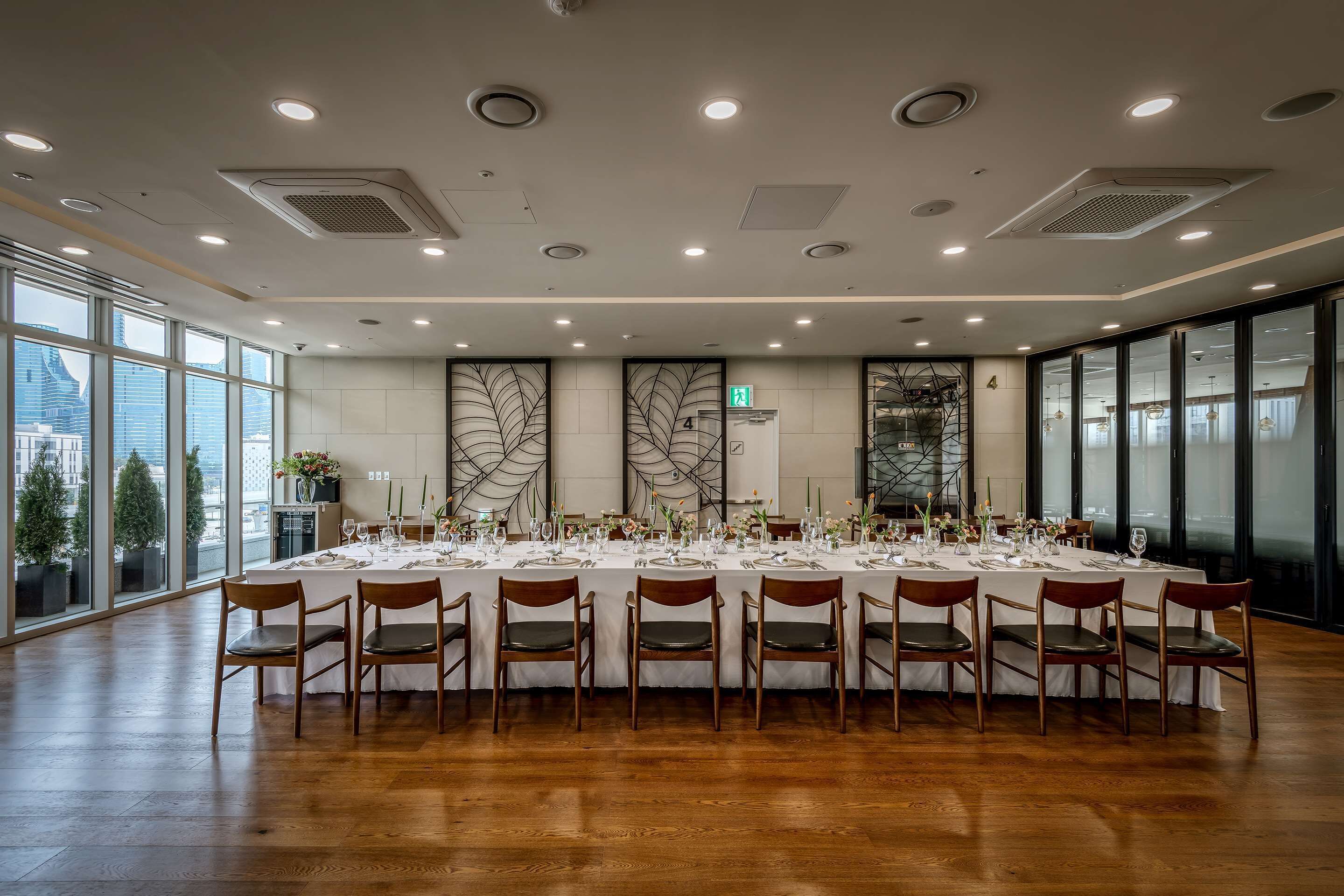 A conference room with a long table set for a meeting, large windows, and a city view.