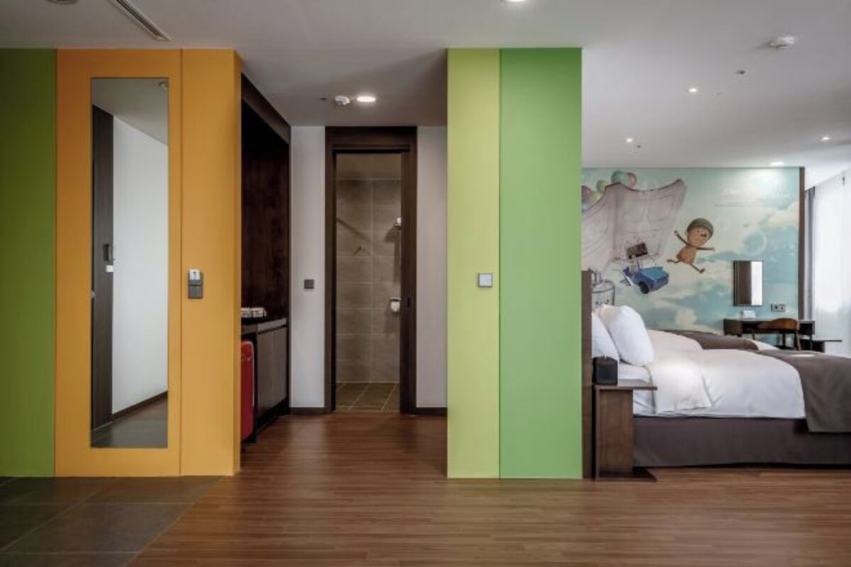 A hotel room with a bed, a desk, and a bathroom with a shower.