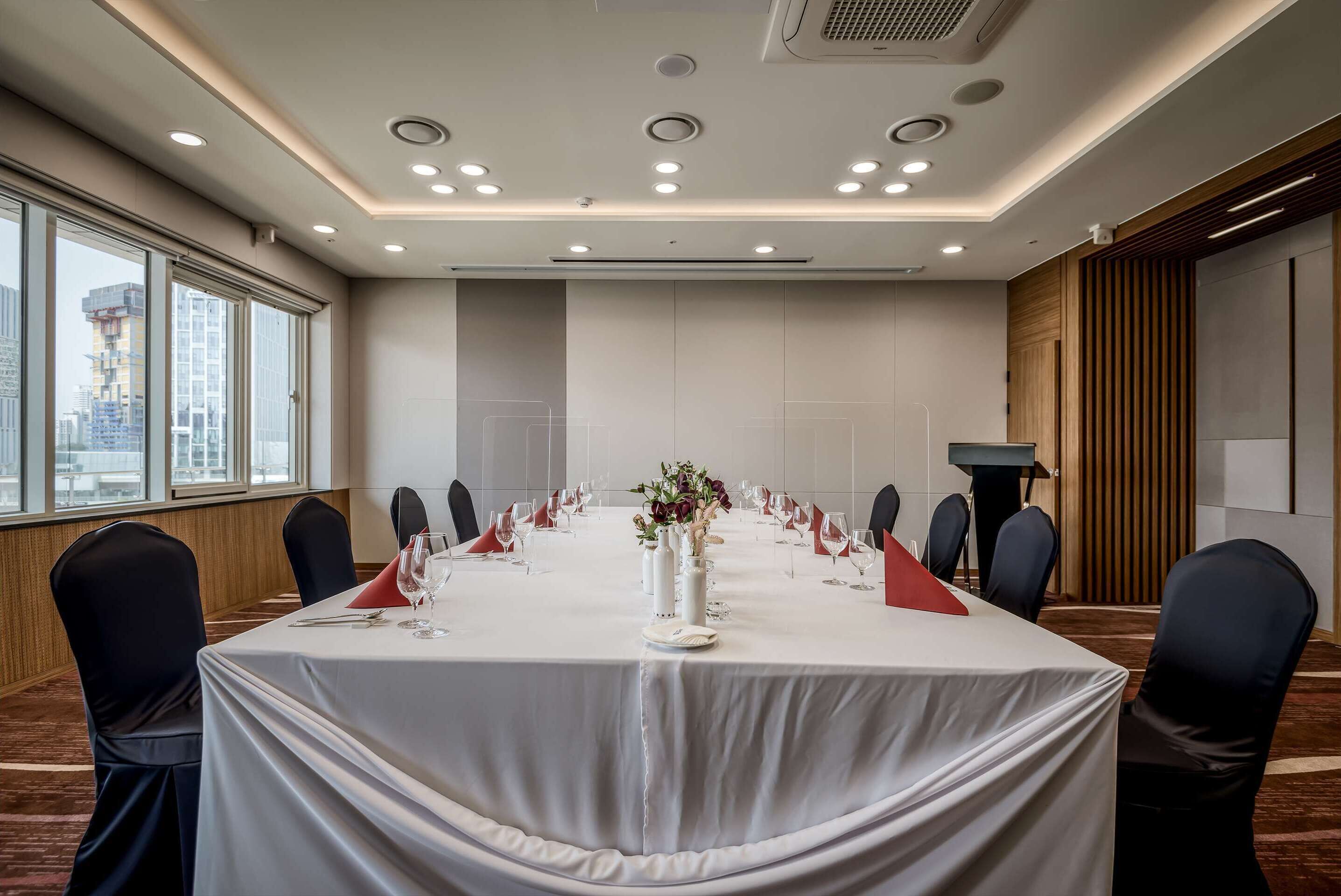Een vergaderzaal met een lange tafel, stoelen en een spreekgestoelte.