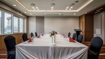 Een vergaderzaal met een lange tafel, stoelen en een spreekgestoelte.
