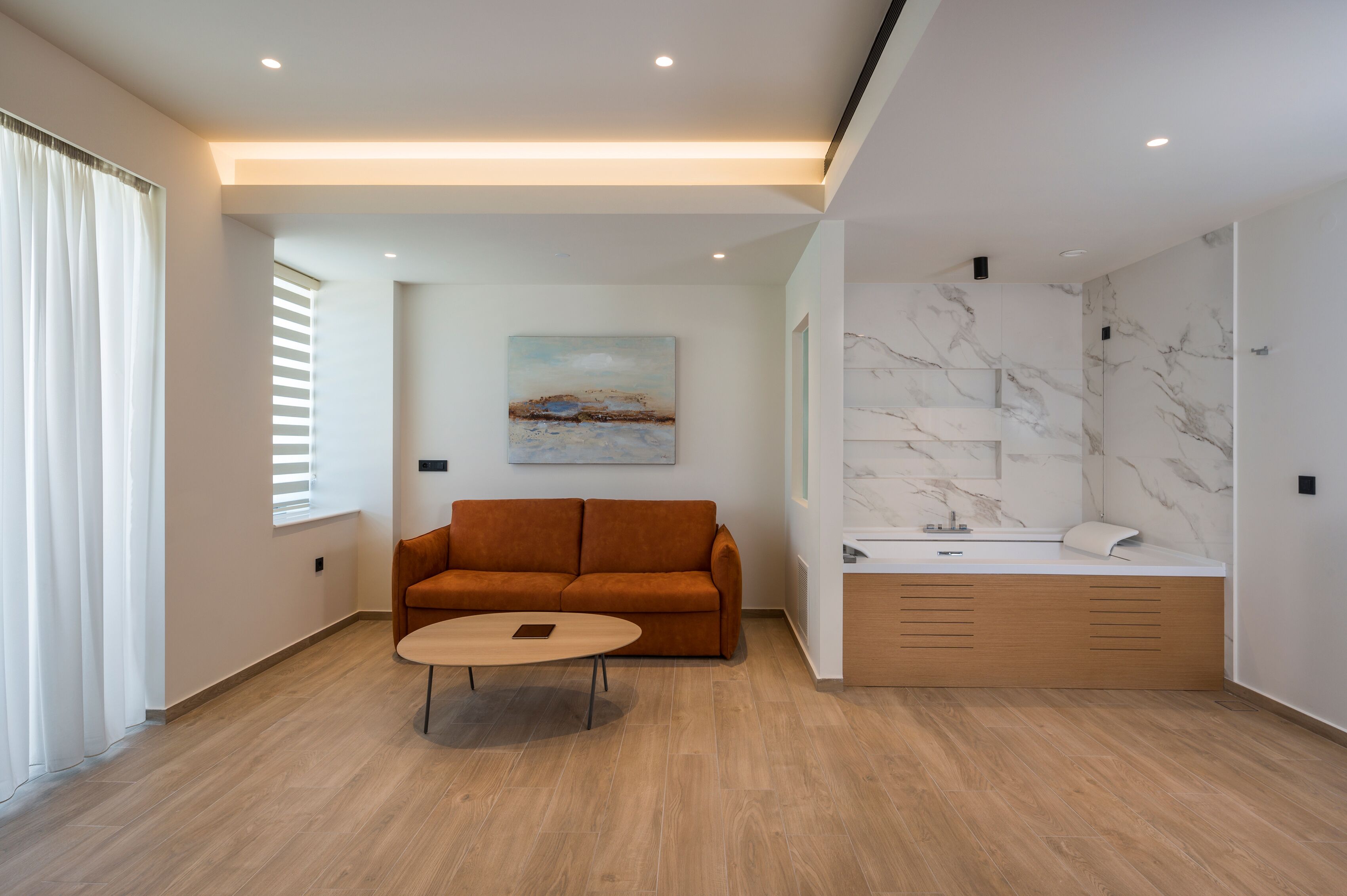 A modern living room with a sofa, coffee table, and a painting on the wall.