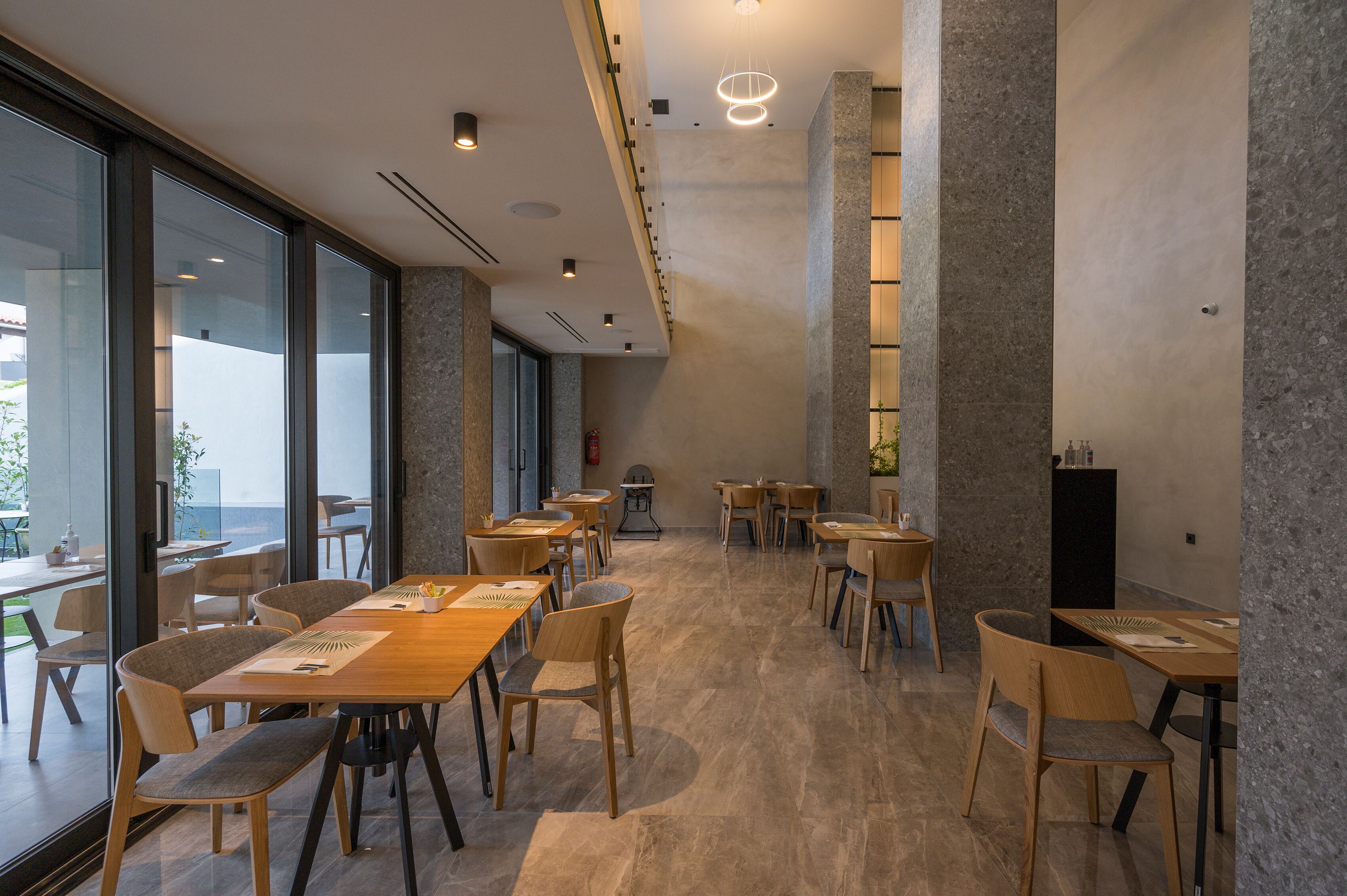 A spacious indoor dining area with high ceilings, large windows, and a modern design.