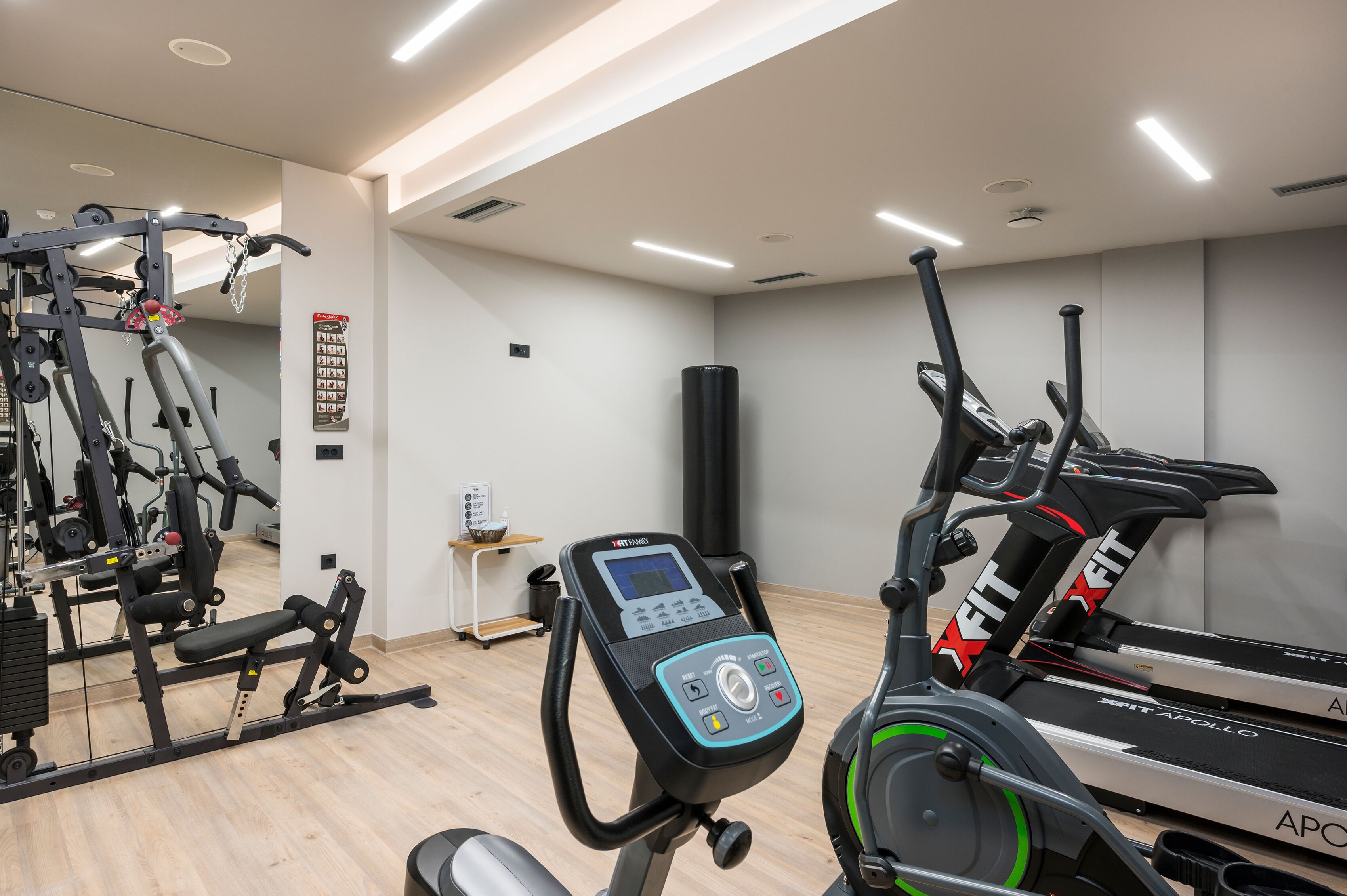 Una palestra con attrezzature cardio, macchinari per pesi e uno specchio.