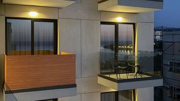 A modern multi-story building with balconies, large windows, and a view of the cityscape.