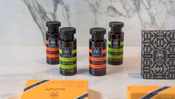Des flacons de shampoing APIVITA au miel grec et à l’orange, ainsi qu’un gel douche à la tisane de montagne, le tout présenté dans une boîte contenant un nécessaire de toilette.