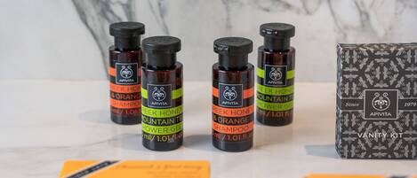 Bottles of APIVITA Greek Honey & Orange Shampoo and Mountain Tea Shower Gel, along with a vanity kit box.