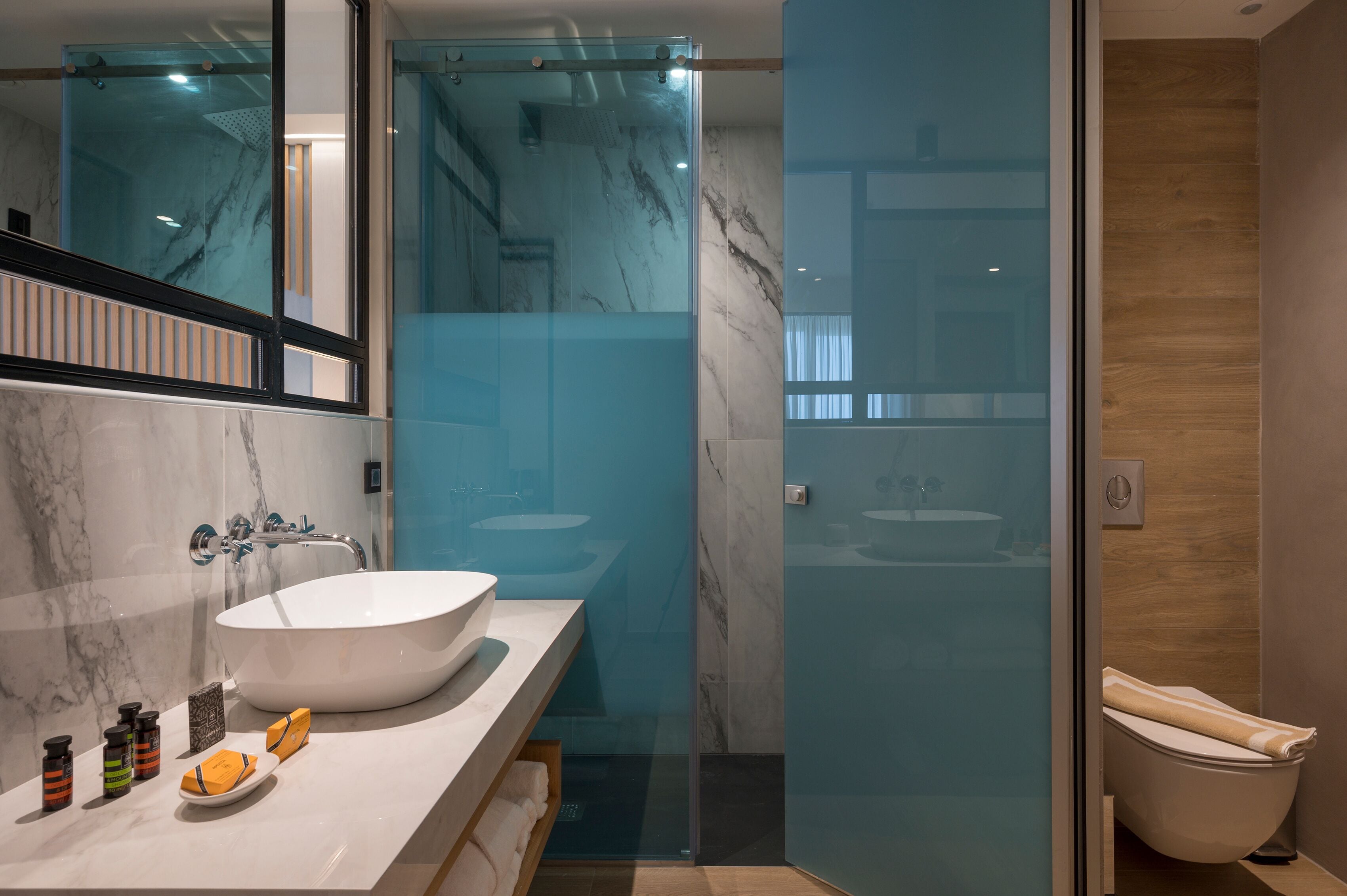 Un baño moderno con un lavabo grande de color blanco, una cabina de ducha con mampara de vidrio y un mueble de tocador de madera.