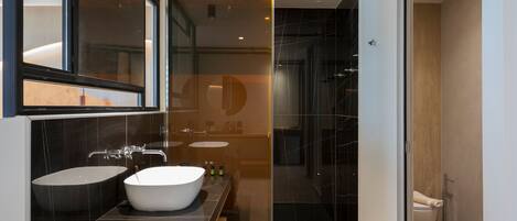A modern bathroom with a large sink, mirror, and shower area.