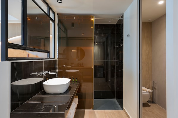 Un baño moderno con un lavamanos grande, espejo y zona de ducha.