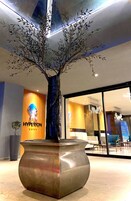 Zona de recepción con un gran árbol en maceta, un letrero 'Hyperion' y diseño de interiores moderno.