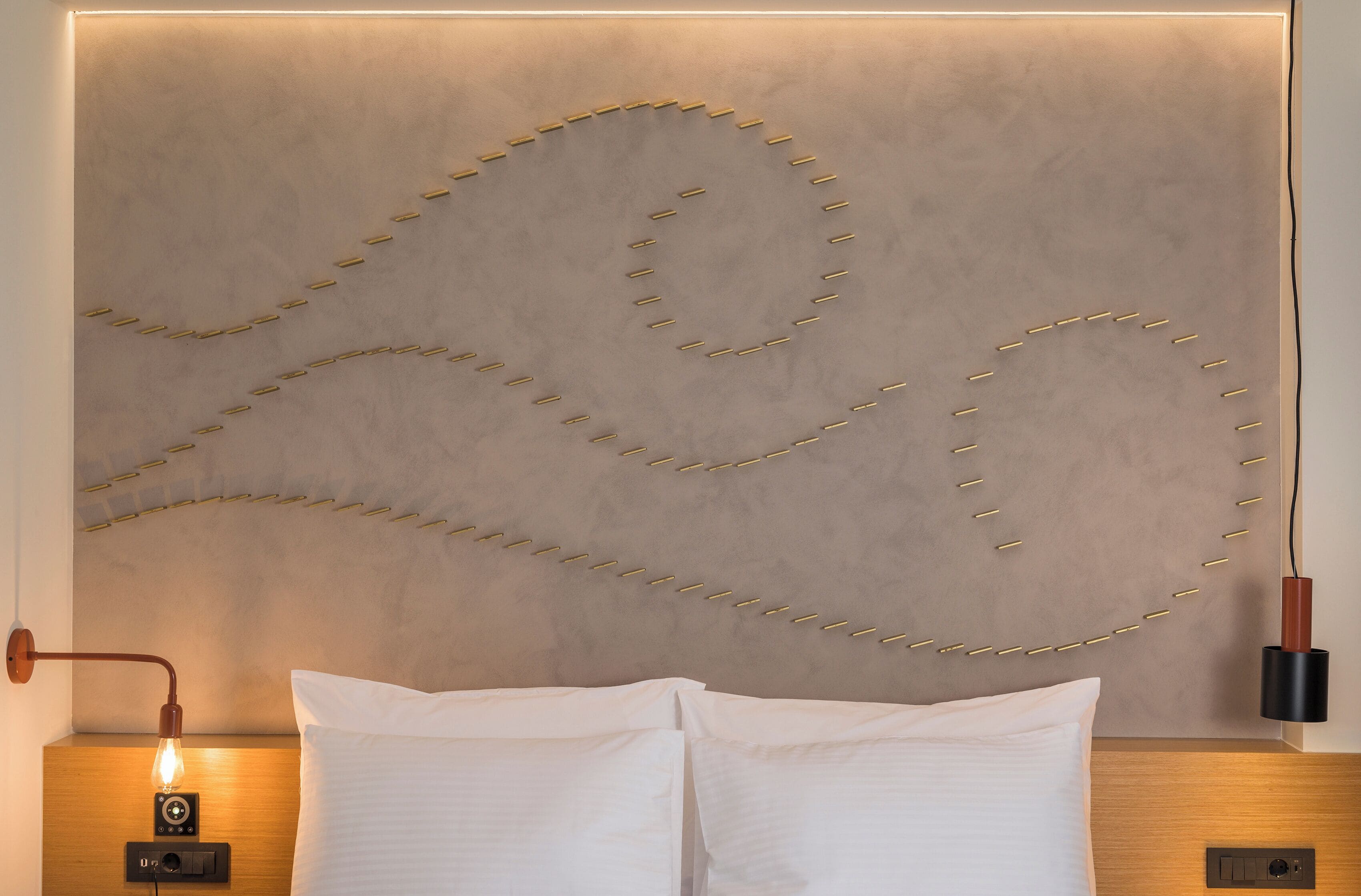 Une chambre d’hôtel moderne dotée d’une tête de lit au design original, d’une lampe de chevet et d’un panneau de commande.