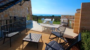 A patio with a table and chairs, a bench, and a view of the sea. - Sea view villa with garden and private hot tub 242 (Marina di Pescoluse)