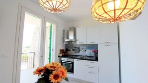 A modern kitchen with white cabinets, a stainless steel sink, and a built-in oven. There are two pendant lights with a woven design. - Sea view villa with garden and private hot tub 242 (Marina di Pescoluse)